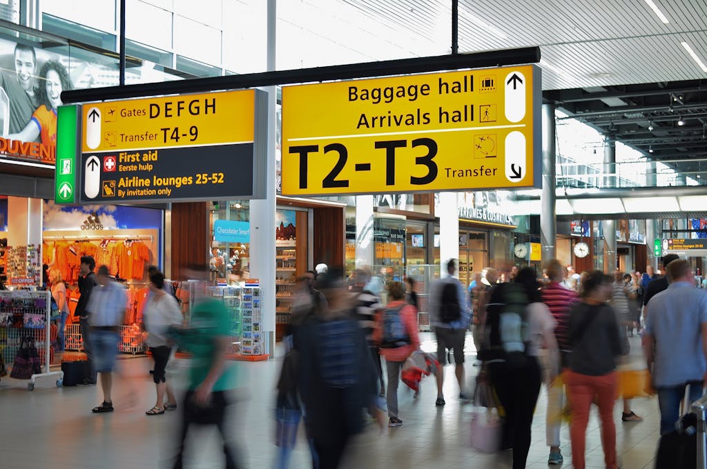 Crowded airport with motion blur and clear signage indicating baggage and arrival halls.